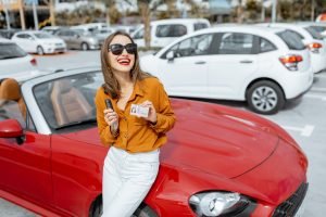 Woman with keys and license near the car at the parking